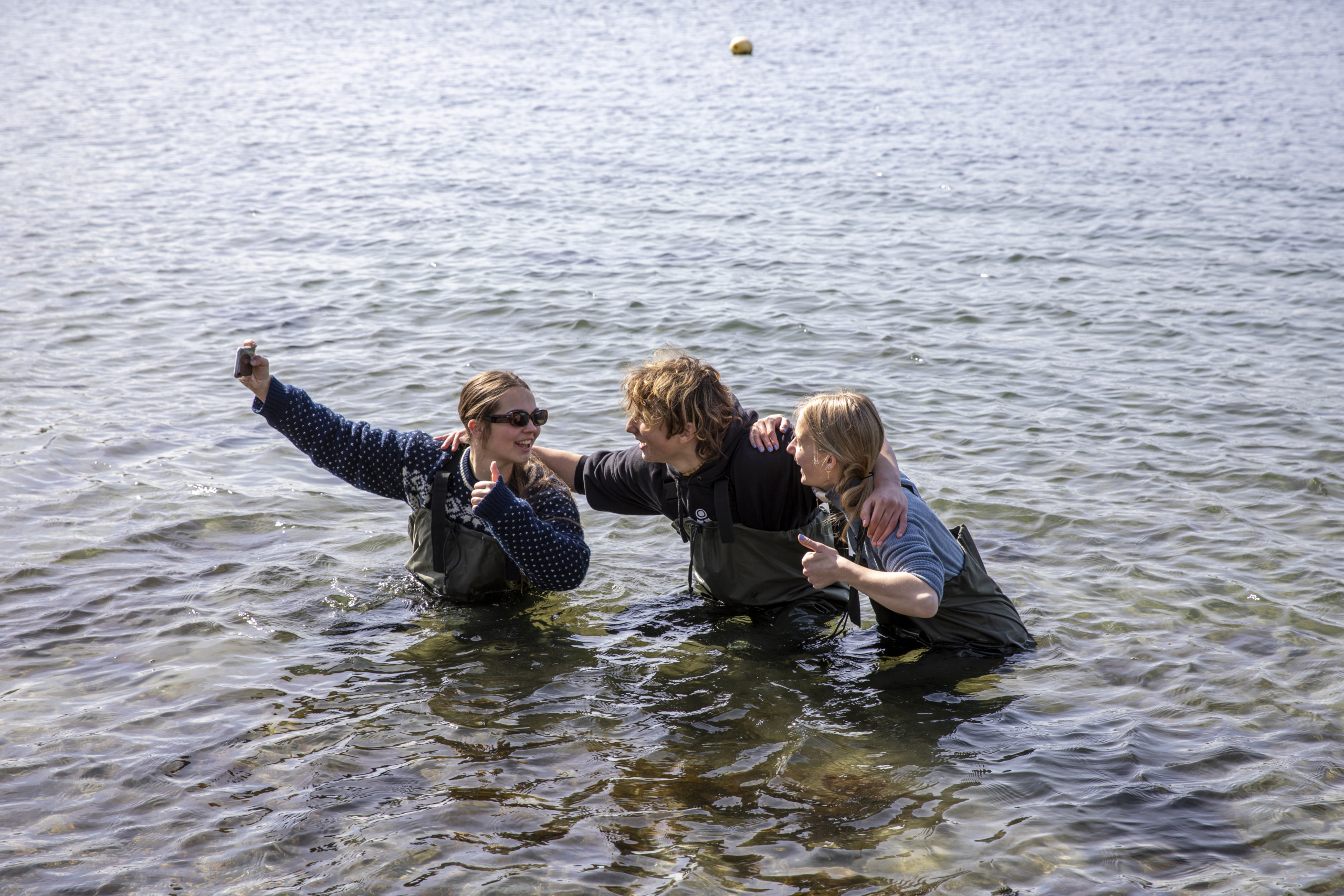 Tre ungdommer tar en selfie mens de står godt ute i vannet i Oslofjorden.