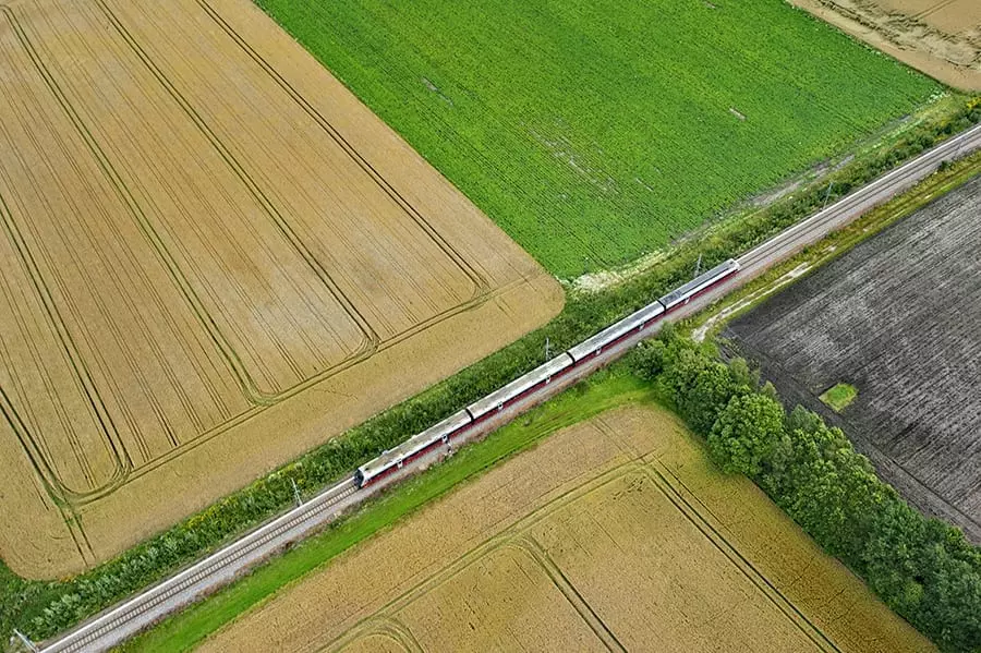 Bilde tatt fra lufta, som viser et tog som kjører forbi dyrka mark