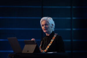 Bilde av Anne Strømøy fra en konferanse hvor hun holder et innlegg.